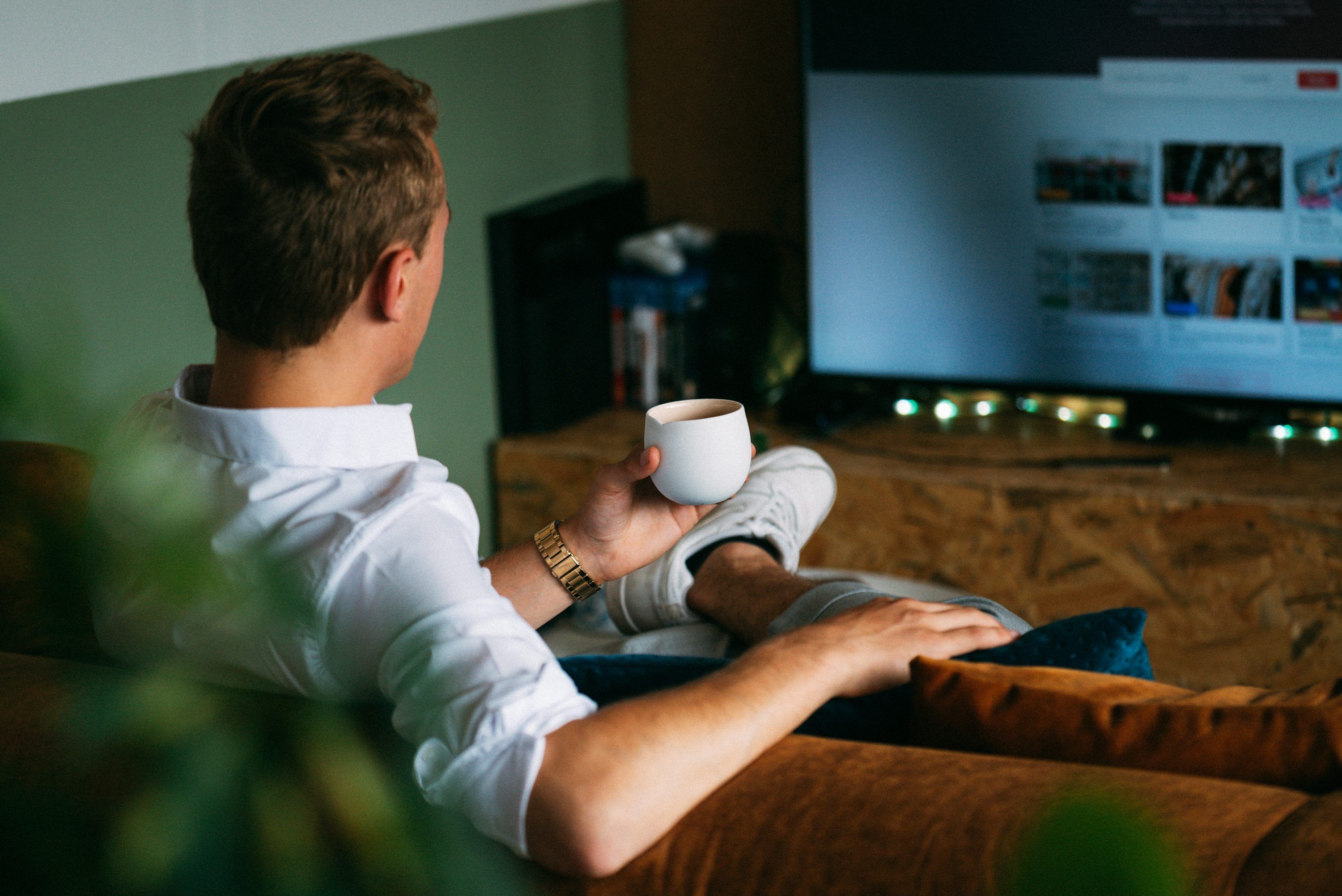 Kvinna som tittar på IPTV-streaming i soffan med fjärrkontroll i handen